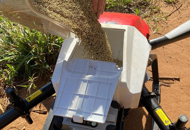 Drone loaded with containers full of grass seeds