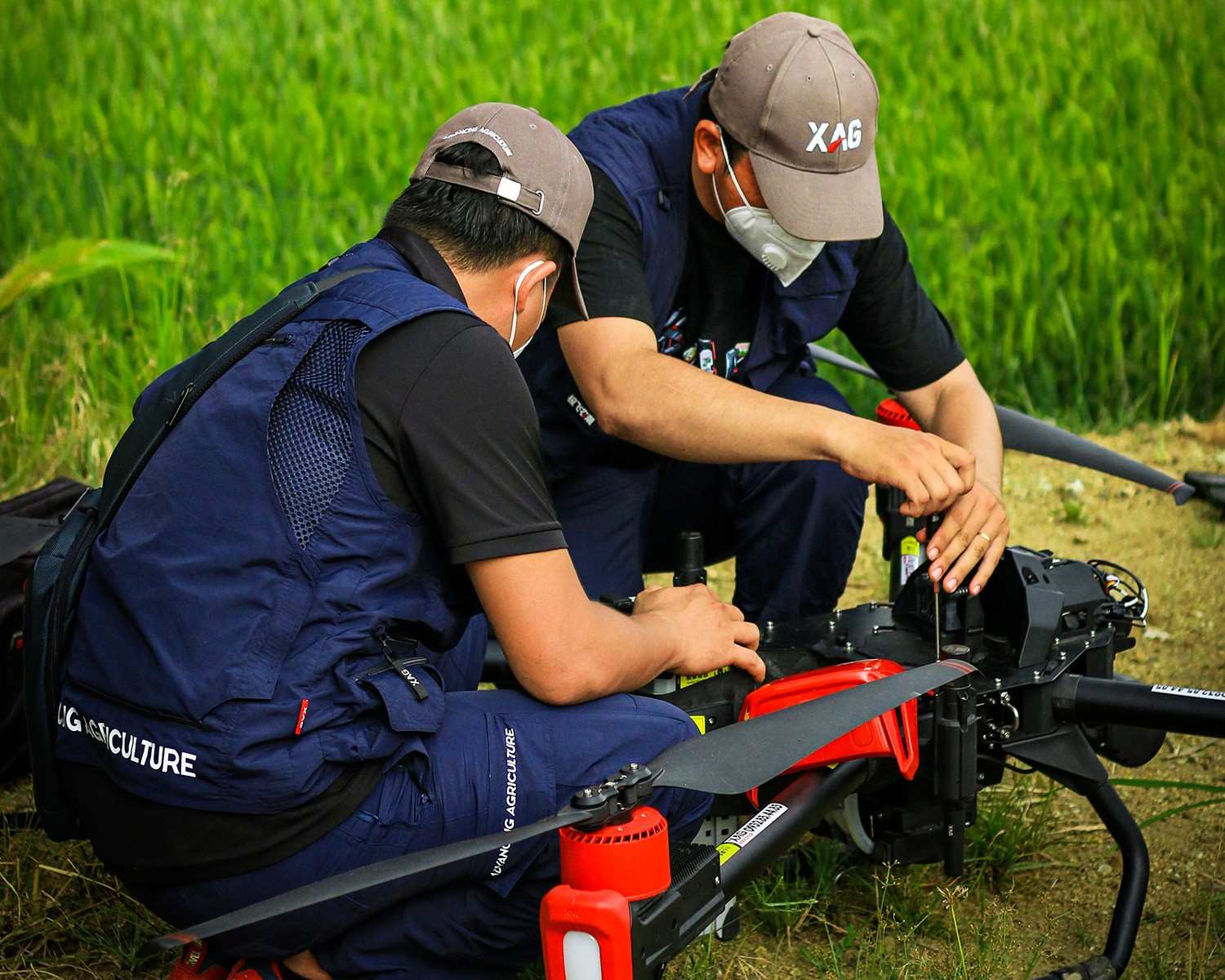 Two young drone pilots are carefully conducting maintenance before taking the new agricultural Skywalker to rice field demonstration.