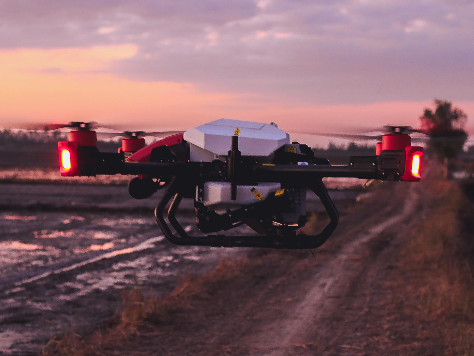 Shimmering in red lights, the XAG P40 agricultural drone with the RevoCast system flies into the sunset for rice seeding. The final round of operation is about to end.