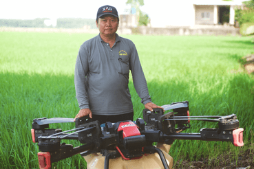 Phan Van Dong together with XAG P100 agricultural drone beside his rice paddy